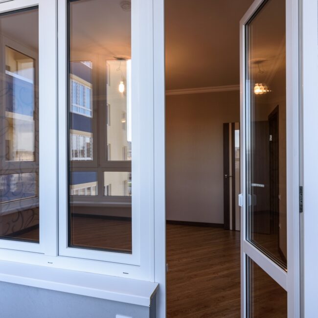 Porta-finestra aperta su stanza vuota con parquet.