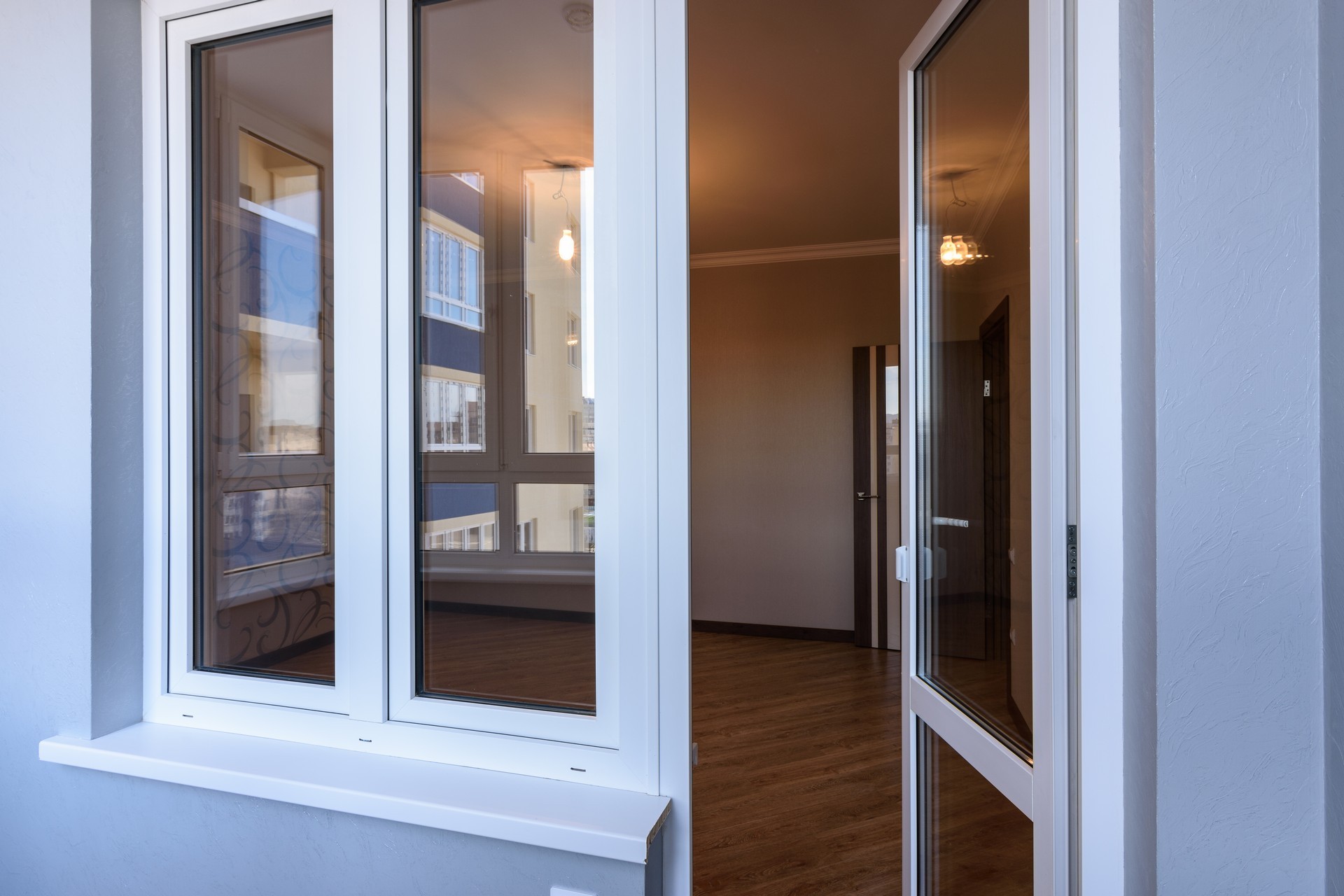 Porta-finestra aperta su stanza vuota con parquet.