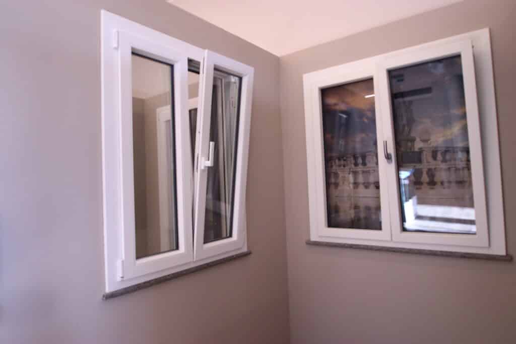 Due finestre bianche su parete interna beige.