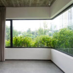 Interno con ampie finestre e vista su piante verdi.