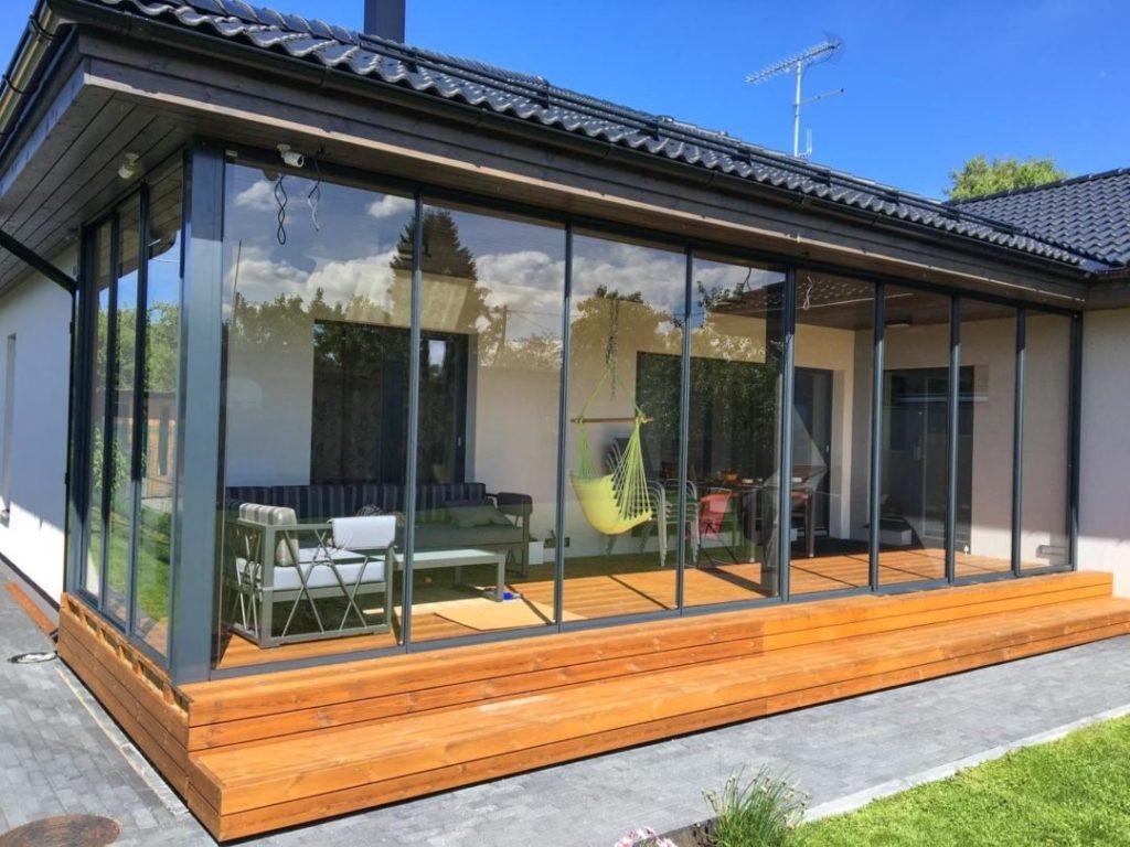 Veranda moderna con pareti in vetro e mobili da esterno.