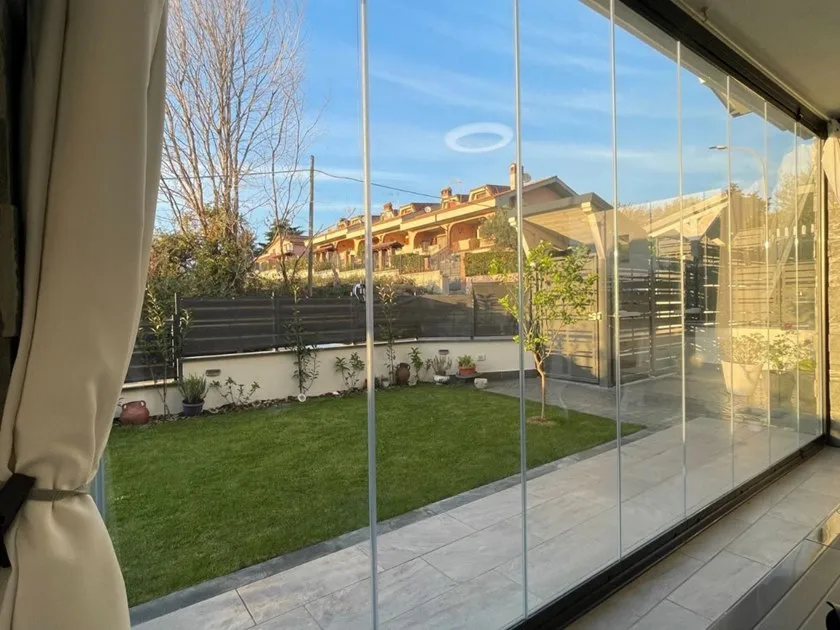 Vista di un giardino attraverso una vetrata trasparente.